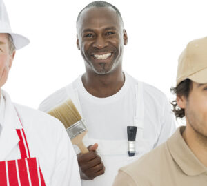 Three people are standing together holding paint brushes.